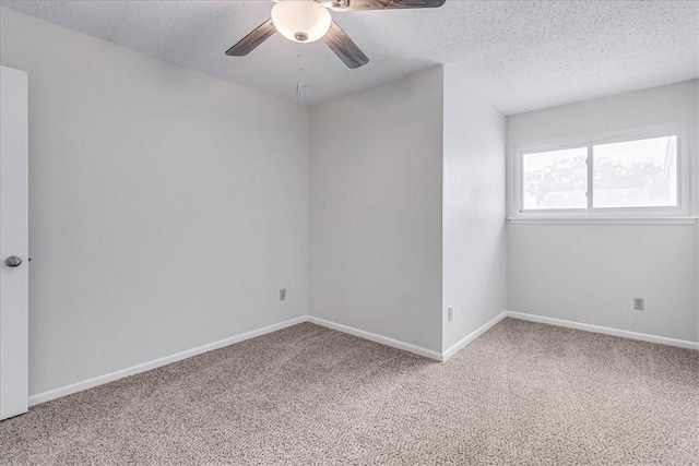 empty room featuring a textured ceiling, carpet floors, ceiling fan, and baseboards