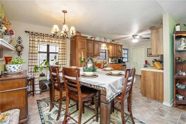 dining room with ceiling fan with notable chandelier, sink, and a textured ceiling