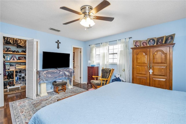 bedroom with ceiling fan, dark hardwood / wood-style flooring, and a textured ceiling