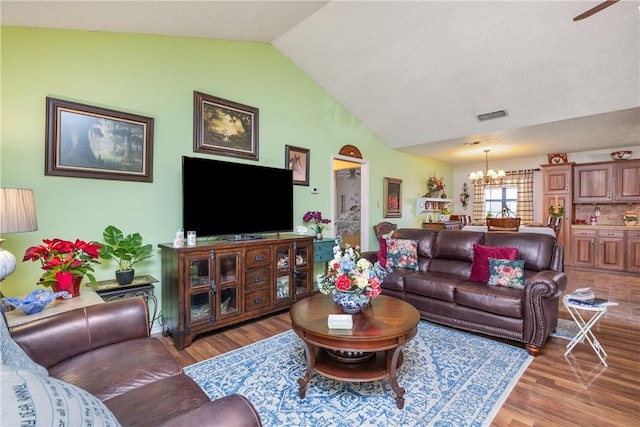 living room featuring wood-type flooring, vaulted ceiling, and a notable chandelier