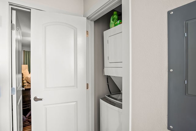 laundry area with electric panel and stacked washer and dryer