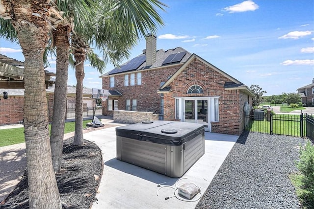10 W Bar Le Doc Dr, Corpus Christi, TX 78414 - back of house with a hot tub, brick siding, a chimney, a fenced backyard, and roof mounted solar panels
