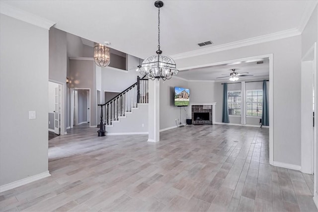 unfurnished living room with crown molding, a fireplace, ceiling fan with notable chandelier, and light hardwood / wood-style flooring