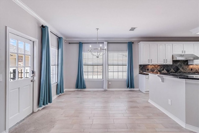 kitchen with white cabinetry, crown molding, a chandelier, and decorative light fixtures