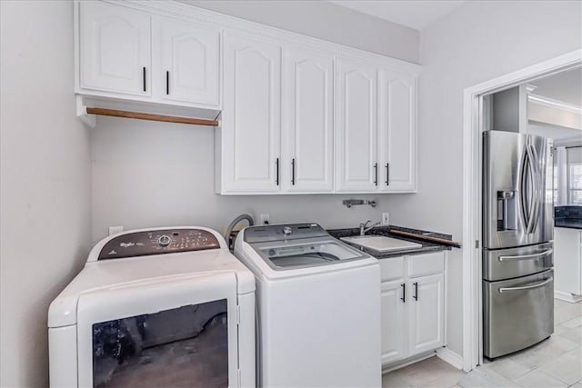 clothes washing area featuring separate washer and dryer, sink, and cabinets