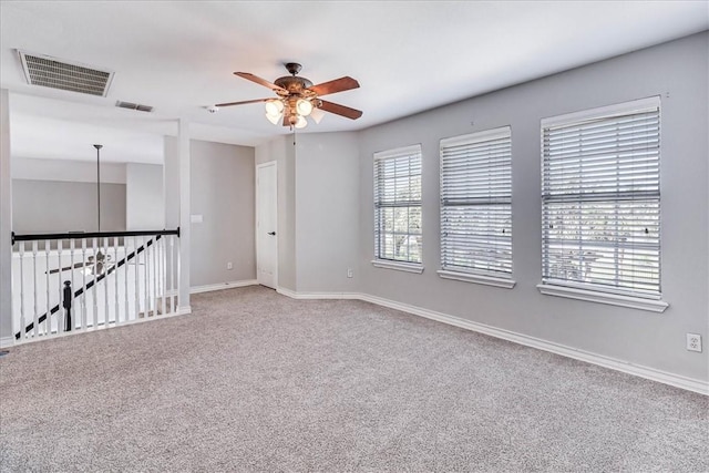 carpeted empty room with a wealth of natural light and ceiling fan