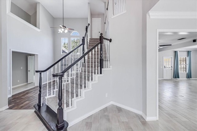 staircase with hardwood / wood-style floors, ceiling fan, and crown molding