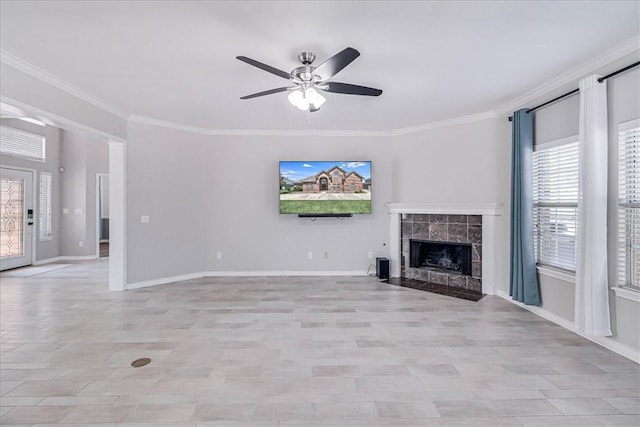 unfurnished living room featuring a wealth of natural light, a fireplace, ceiling fan, and crown molding