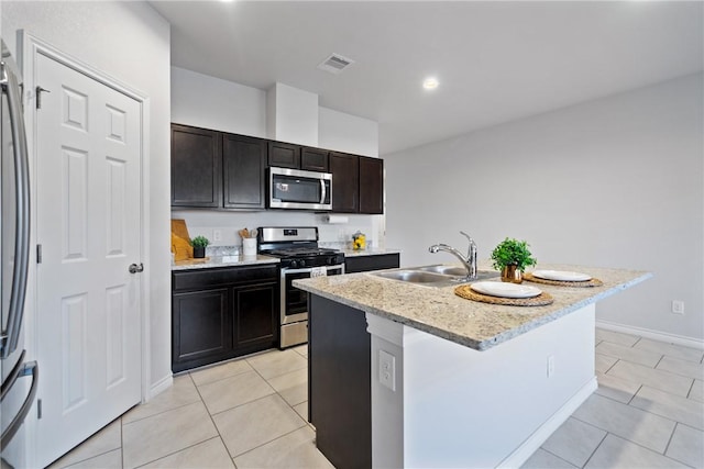 kitchen with light tile patterned floors, visible vents, an island with sink, stainless steel appliances, and a sink