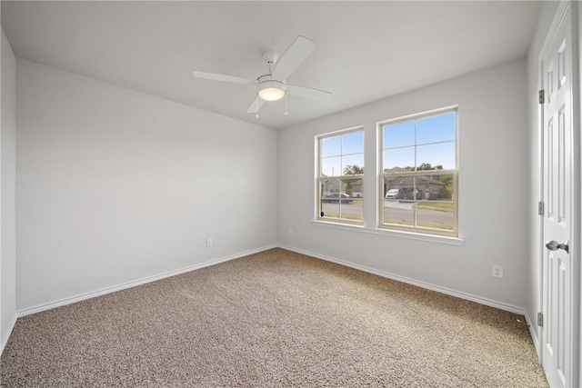 carpeted spare room featuring ceiling fan and baseboards