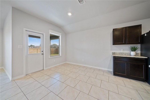 unfurnished dining area featuring baseboards, visible vents, vaulted ceiling, and light tile patterned flooring