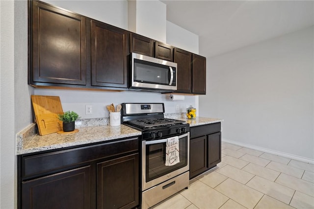 kitchen with baseboards, stainless steel appliances, dark brown cabinetry, and light stone countertops