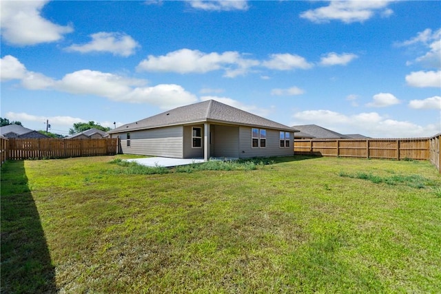 rear view of property with a fenced backyard, a lawn, and a patio