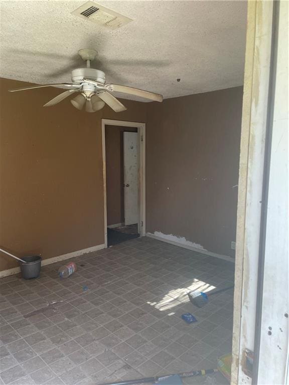 spare room featuring baseboards, visible vents, and a textured ceiling