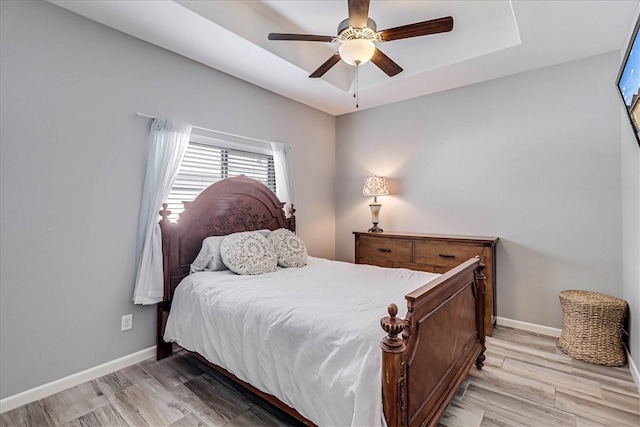 bedroom with a tray ceiling, light hardwood / wood-style flooring, and ceiling fan