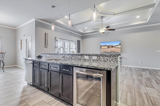 kitchen featuring light stone countertops, beverage cooler, crown molding, sink, and decorative light fixtures