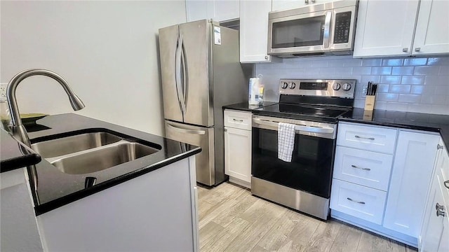 709 Lauderdale Dr, Rockport, TX 78382 - kitchen with stainless steel appliances, dark countertops, white cabinets, light wood finished floors, and backsplash