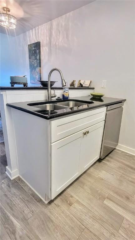 709 Lauderdale Dr, Rockport, TX 78382 - kitchen featuring light wood-style flooring, stainless steel dishwasher, white cabinetry, and dark countertops
