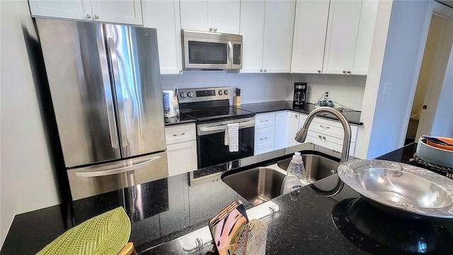 kitchen featuring dark stone countertops, white cabinetry, sink, and stainless steel appliances