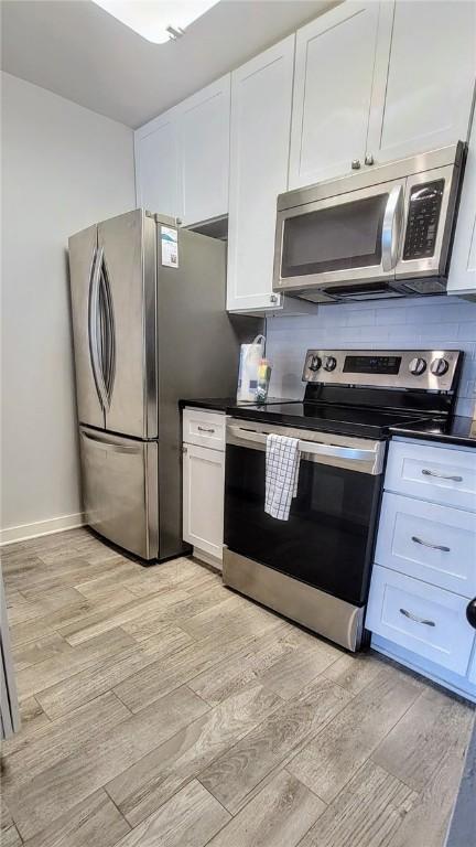 709 Lauderdale Dr, Rockport, TX 78382 - kitchen featuring appliances with stainless steel finishes, light wood-type flooring, white cabinets, and dark countertops