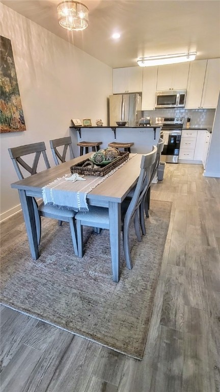 dining area with light hardwood / wood-style flooring and a notable chandelier