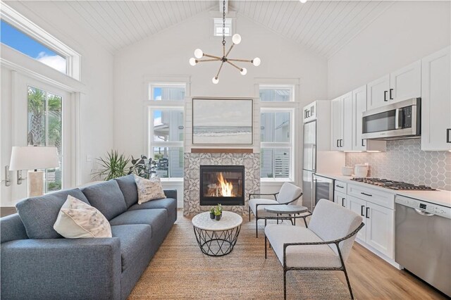 673 Center S Unit 21, Port Aransas, TX 78373 - living area with high vaulted ceiling, light wood-type flooring, a glass covered fireplace, a chandelier, and wine cooler