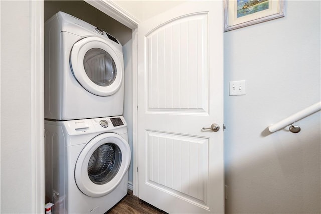 clothes washing area with dark hardwood / wood-style flooring and stacked washer / drying machine