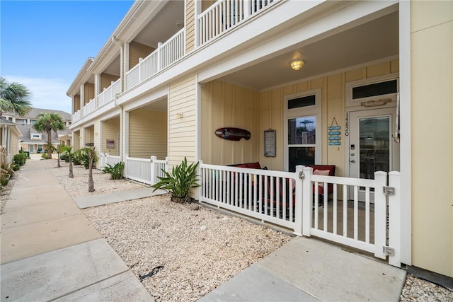 view of exterior entry with a balcony and covered porch