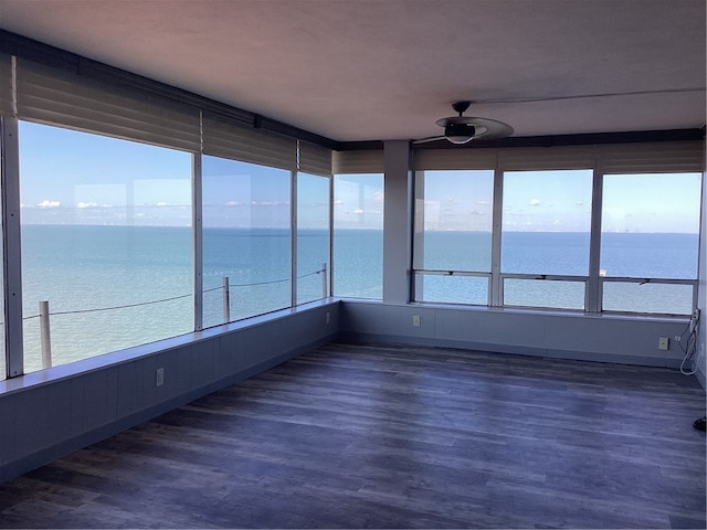 unfurnished sunroom with a water view and ceiling fan