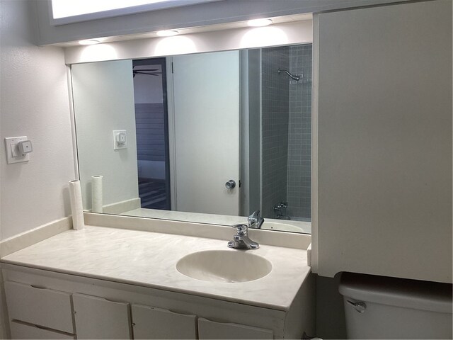 bathroom with toilet, vanity, and tiled shower