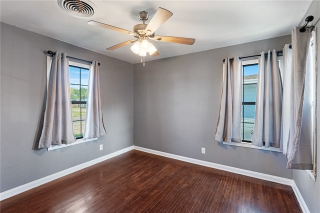 empty room featuring dark hardwood / wood-style flooring, ceiling fan, and a healthy amount of sunlight