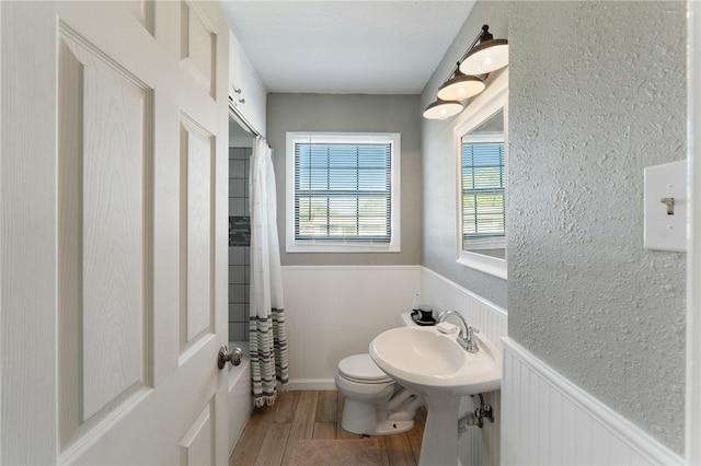 bathroom with toilet, sink, hardwood / wood-style flooring, and walk in shower