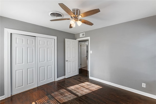 unfurnished bedroom with dark wood-type flooring, a closet, and ceiling fan