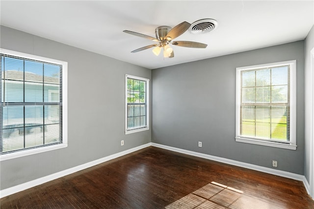 empty room with dark hardwood / wood-style flooring, a wealth of natural light, and ceiling fan