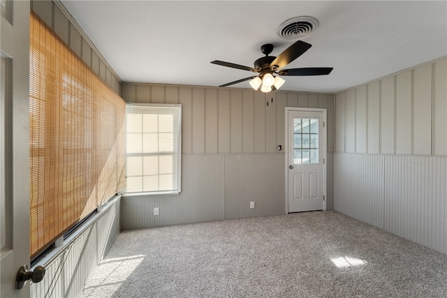 carpeted empty room with wood walls and ceiling fan