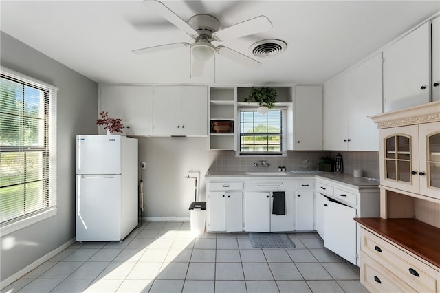 kitchen featuring white cabinetry, a wealth of natural light, light tile patterned floors, and white refrigerator