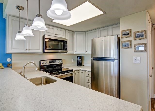 kitchen featuring white cabinets, appliances with stainless steel finishes, sink, and hanging light fixtures