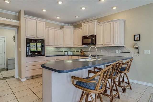 kitchen with light tile patterned floors, a peninsula, a breakfast bar, a sink, and black appliances