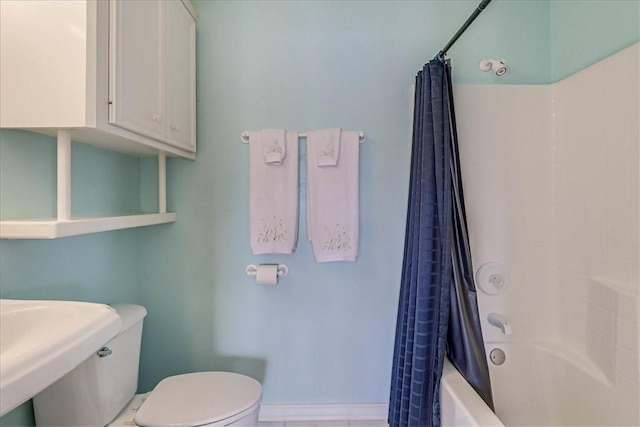 bathroom featuring shower / bath combination with curtain, toilet, and baseboards