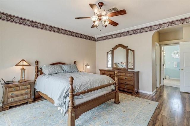 bedroom with arched walkways, visible vents, baseboards, ornamental molding, and hardwood / wood-style floors