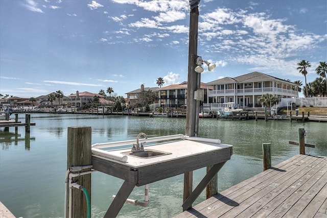 view of dock featuring a water view, a residential view, and a sink