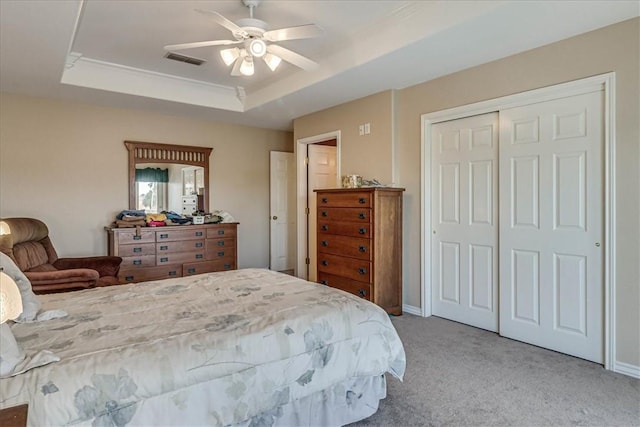 bedroom featuring carpet floors, a raised ceiling, visible vents, a closet, and ceiling fan