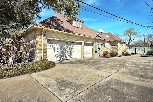 view of property exterior featuring driveway, fence, and brick siding