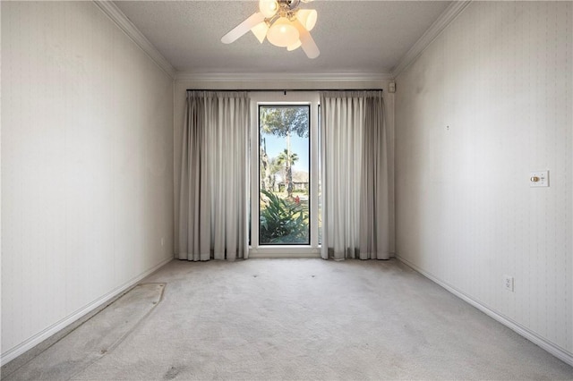 spare room with ceiling fan, crown molding, and light colored carpet