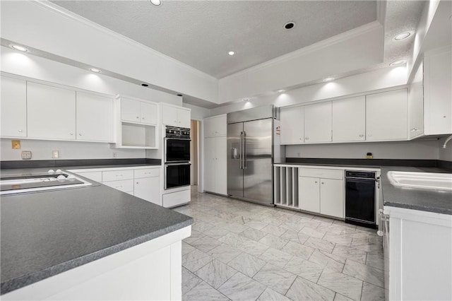 kitchen with white cabinets, dark countertops, ornamental molding, black appliances, and a sink