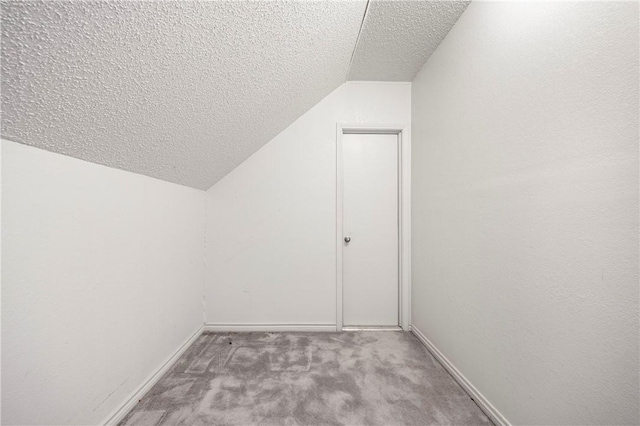 additional living space with light carpet, vaulted ceiling, a textured ceiling, and baseboards