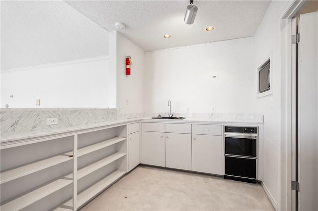 kitchen featuring white cabinets, light countertops, a sink, and a textured ceiling