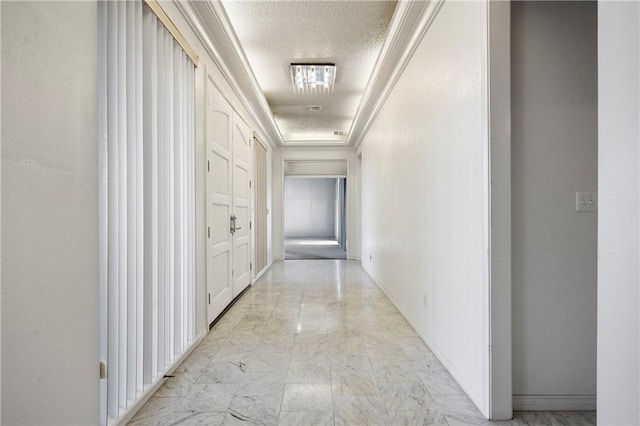 corridor with a textured ceiling, marble finish floor, ornamental molding, and baseboards