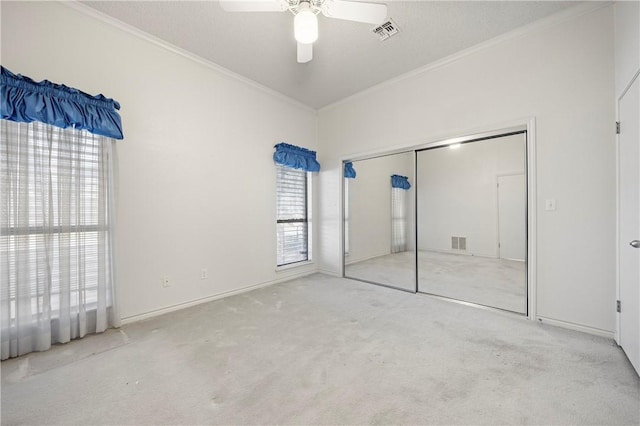 unfurnished bedroom featuring a ceiling fan, visible vents, crown molding, and light colored carpet