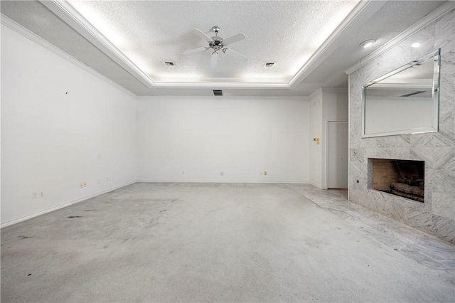 unfurnished living room featuring a tray ceiling, a fireplace, and a textured ceiling